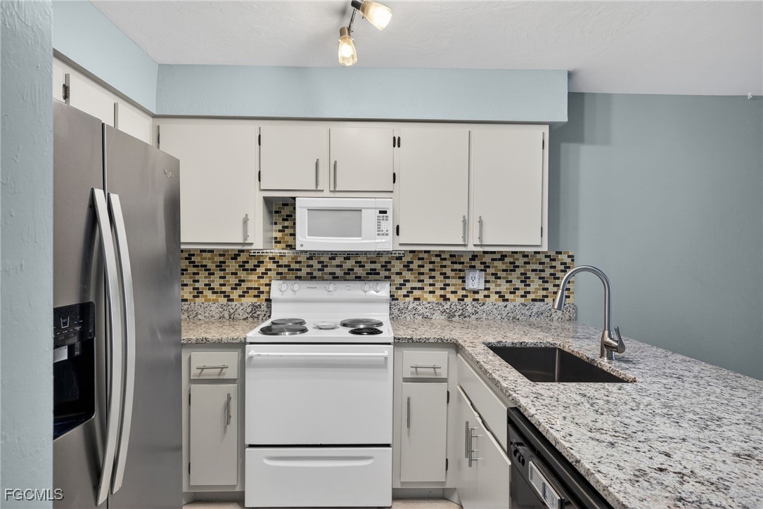 1100 Pondella Road, Unit 811 Cape Coral, FL 33909 - Photo 3 of 24 a kitchen with granite countertop a sink stove and refrigerator