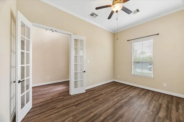 an empty room with wooden floor chandelier fan and windows