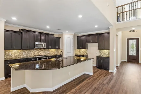 a kitchen with stainless steel appliances granite countertop a sink a stove and a wooden floors