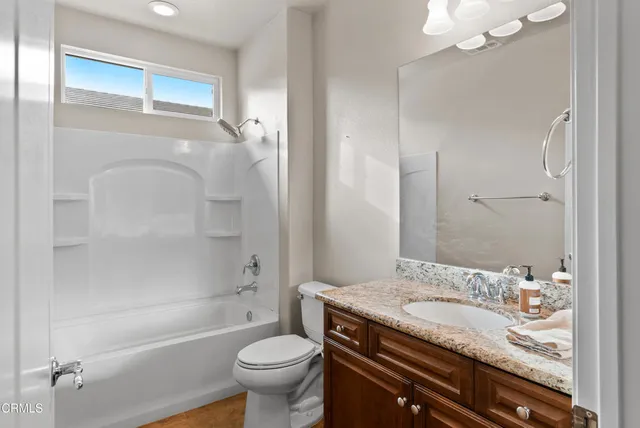 a bathroom with a granite countertop sink a toilet and shower