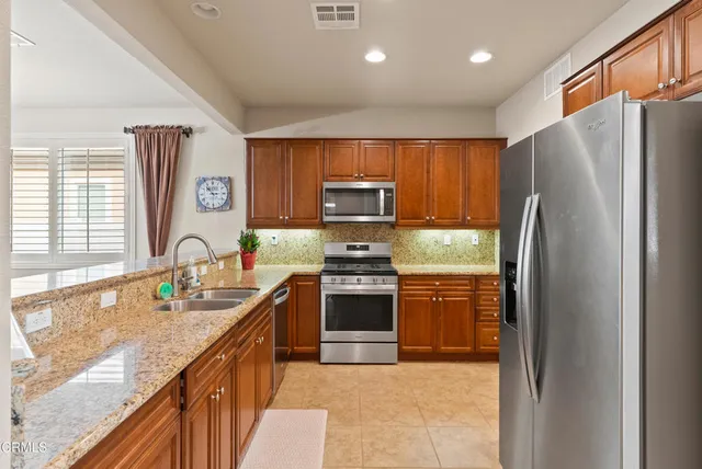 a kitchen with stainless steel appliances granite countertop a refrigerator stove and sink