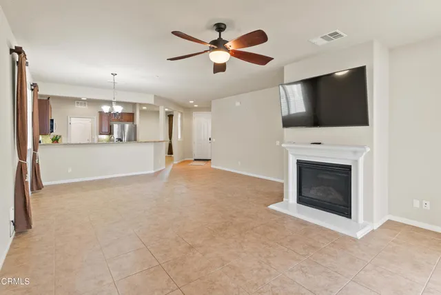 a view of a livingroom with a fireplace a ceiling fan and window