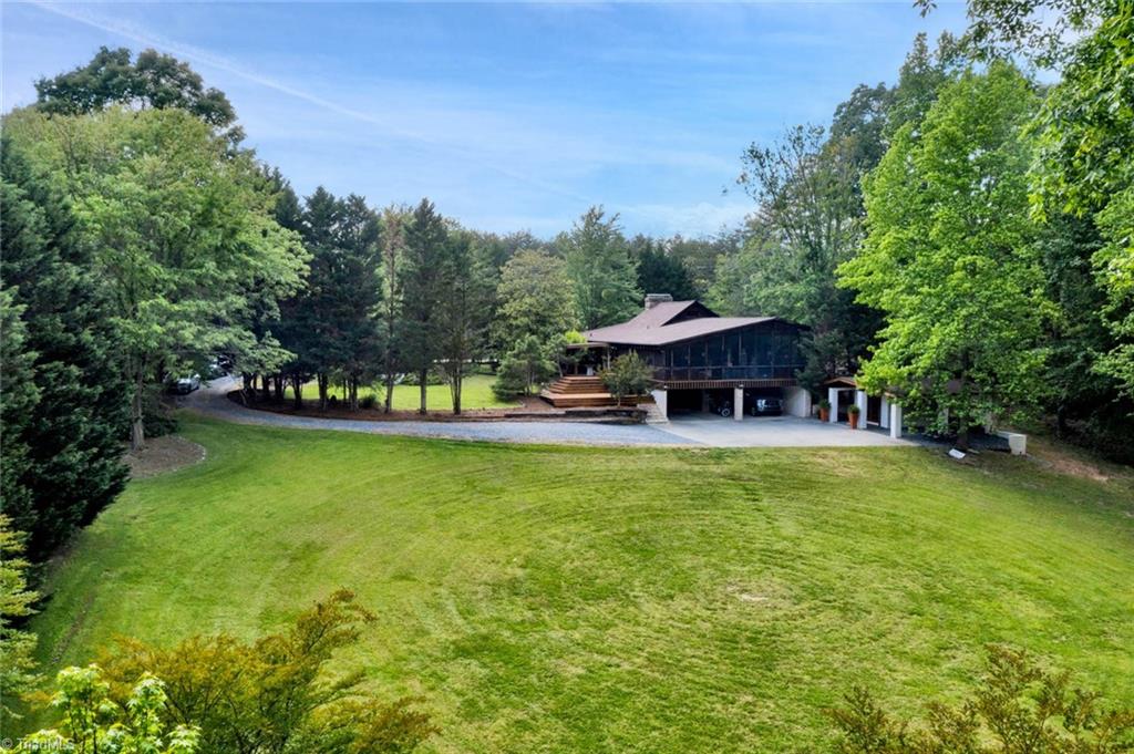 7762 Eversfield Road Summerfield, NC 27358 - Photo 5 of 30 Drone picture from back of the property showing the huge screened porch, carports and utility building built in 2019 with additional carport/tractor shed.