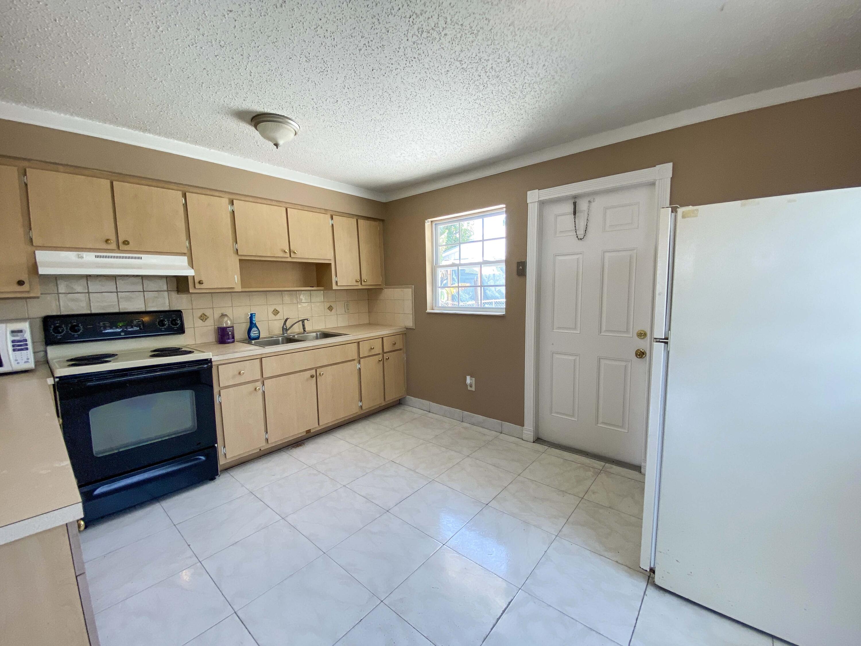 5884 Mango Road, Unit B West Palm Beach, FL 33413 - Photo 3 of 8 a kitchen with stainless steel appliances a stove sink and cabinets