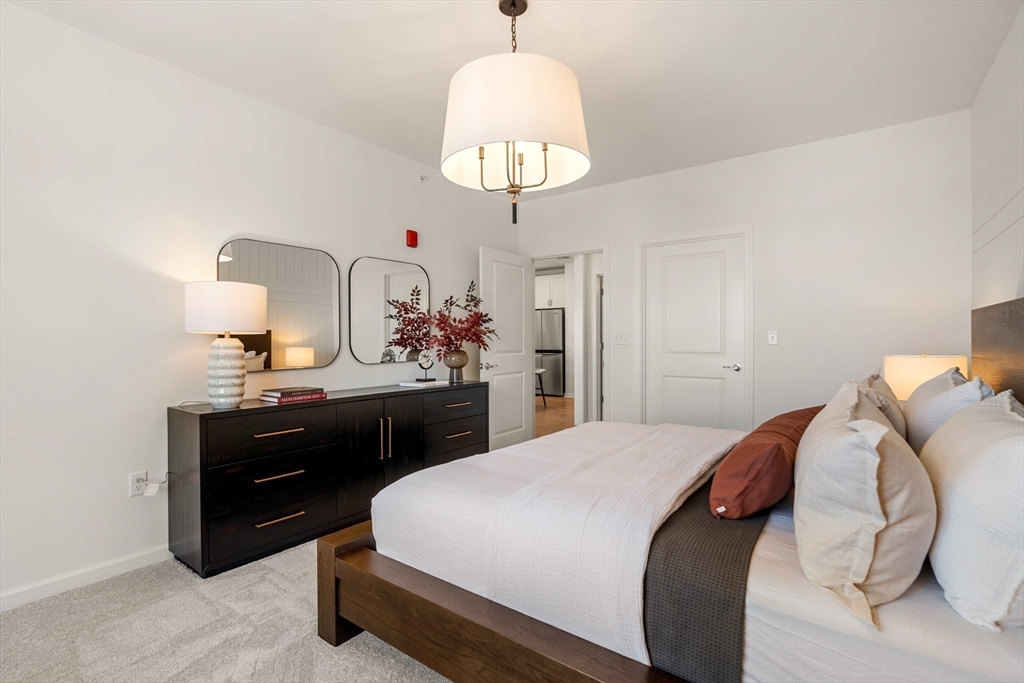 6 Stratton Drive, Unit 3303 Woburn, MA 01801 - Photo 18 of 30 a bedroom with a bed and a chandelier