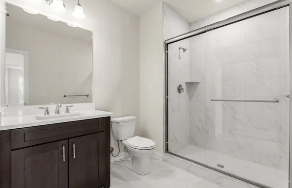 a bathroom with a shower sink vanity mirror and toilet
