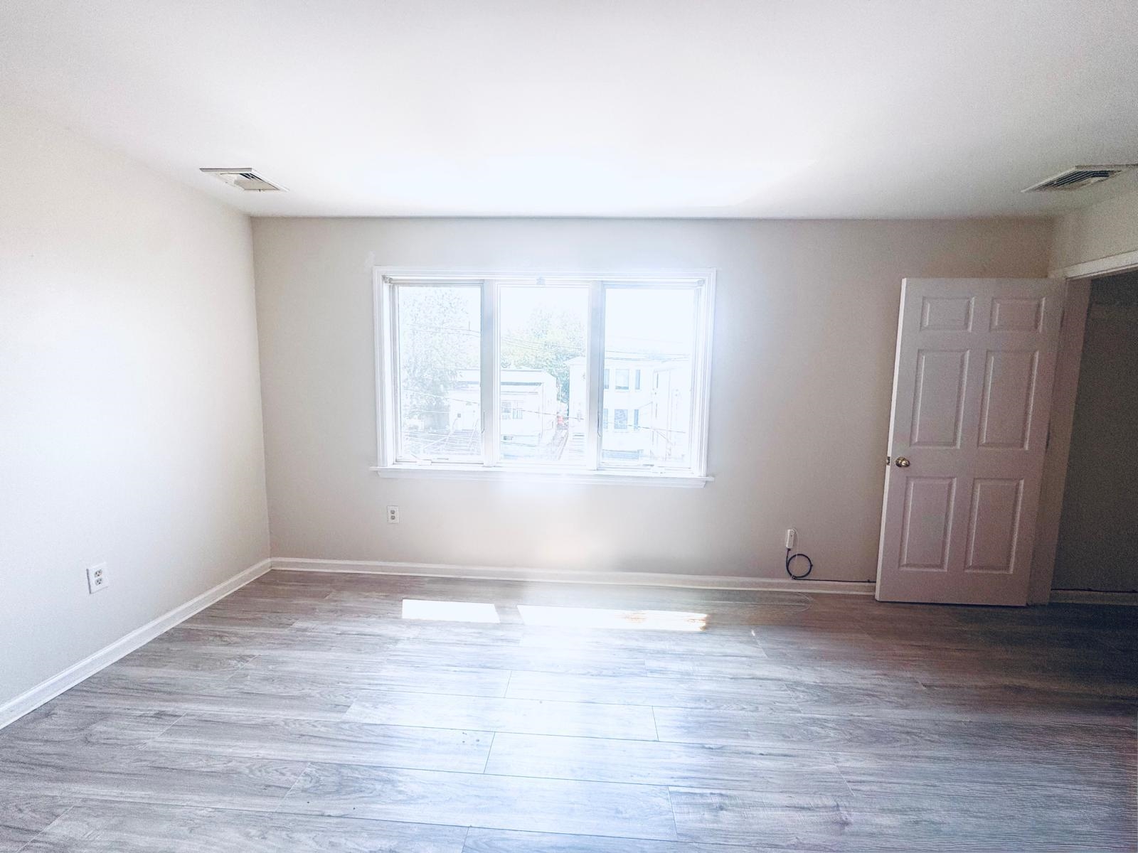 161 West 53rd Street, Unit 2 Bayonne, NJ 07002 - Photo 3 of 19 a view of an empty room with wooden floor and a window