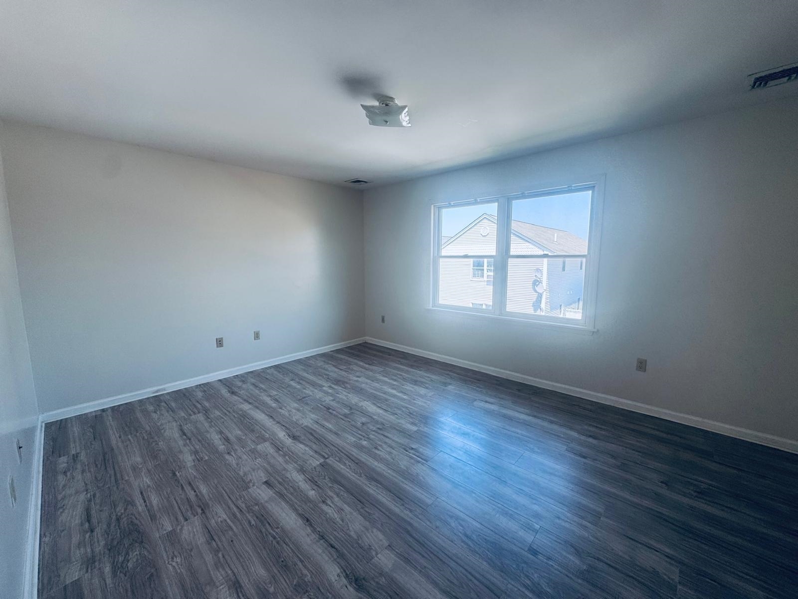 161 West 53rd Street, Unit 2 Bayonne, NJ 07002 - Photo 5 of 19 an empty room with wooden floor and windows