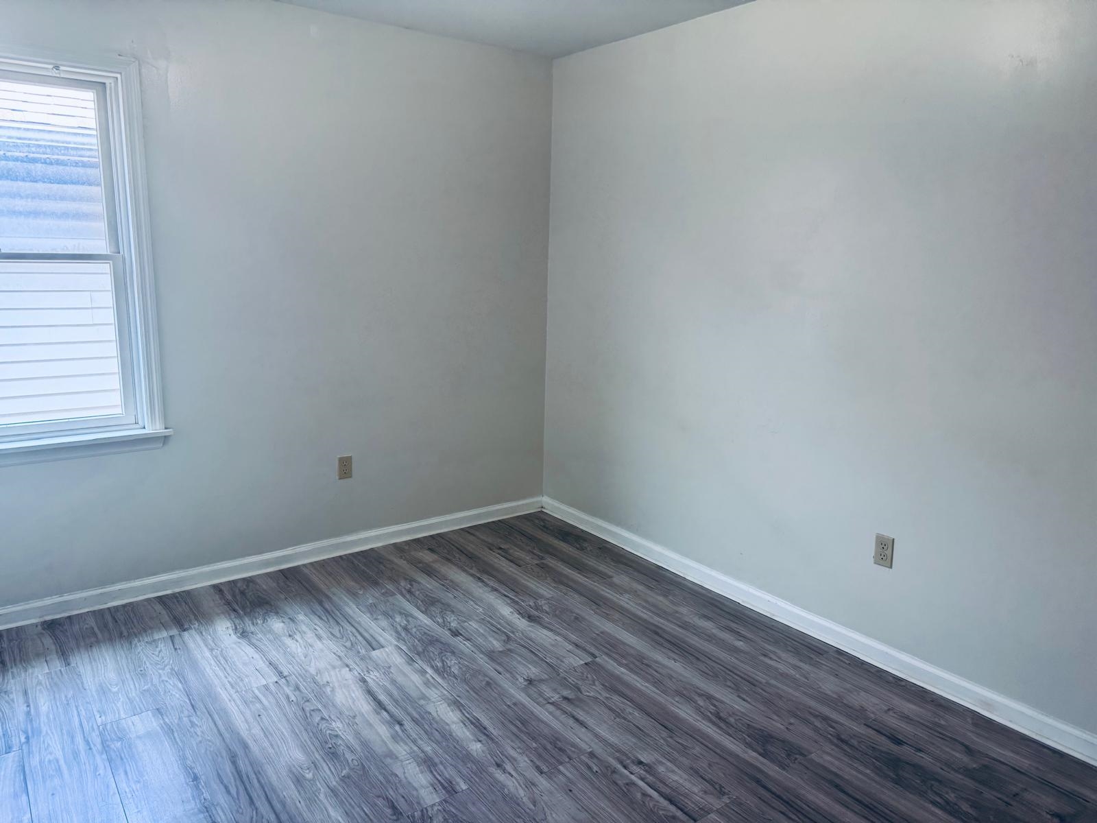 161 West 53rd Street, Unit 2 Bayonne, NJ 07002 - Photo 10 of 19 a view of an empty room with wooden floor and a window
