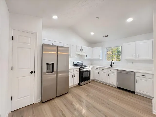a large kitchen with cabinets wooden floor and stainless steel appliances