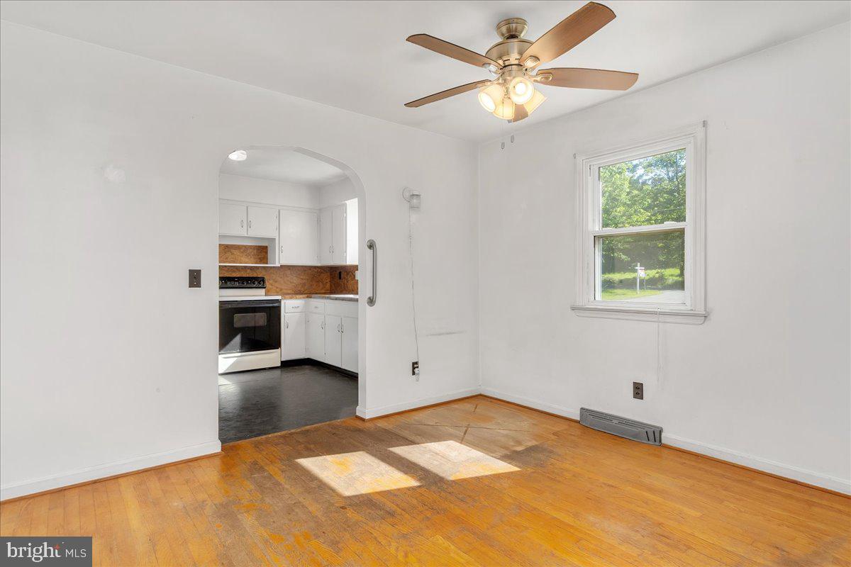 13806 Wolfsville Road Smithsburg, MD 21783 - Photo 10 of 35 a view of a kitchen with a stove cabinets wooden floor and a ceiling fan
