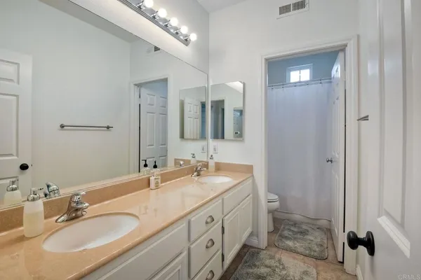a bathroom with a granite countertop double vanity sink and mirror