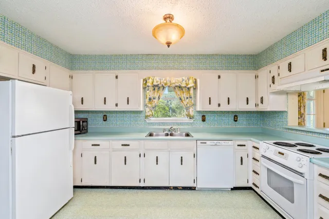 a kitchen with granite countertop a white stove top oven sink and cabinets