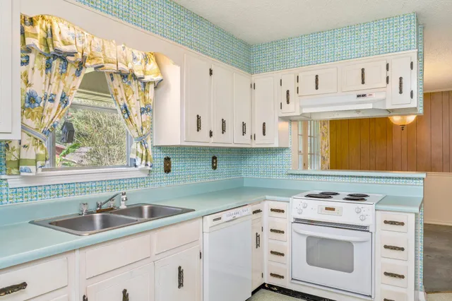 a kitchen with cabinets appliances a sink and a window
