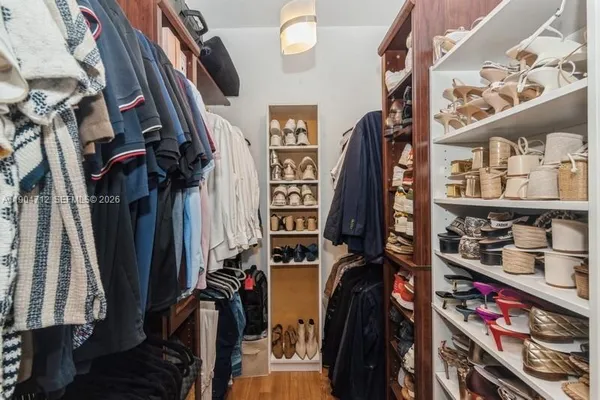 a view of walk in closet with clothes and shoes