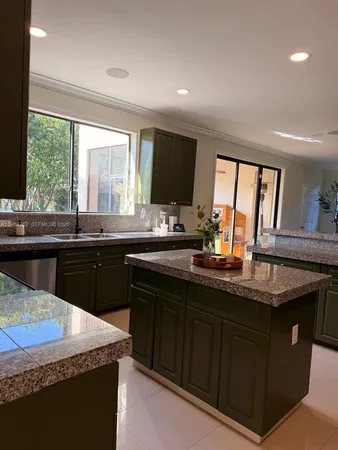 a kitchen with kitchen island granite countertop a sink counter top space and cabinets