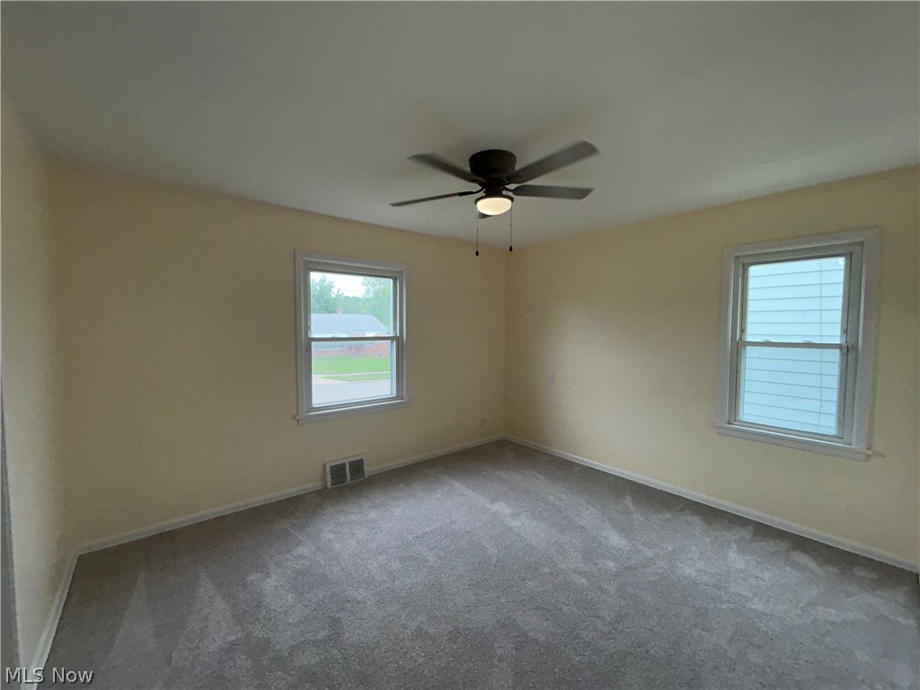 9316 Alexander Road Garfield Heights, OH 44125 - Photo 11 of 27 Neutral wall tones, grey carpet, ceiling fan with integrated lighting, and two windows with white trim