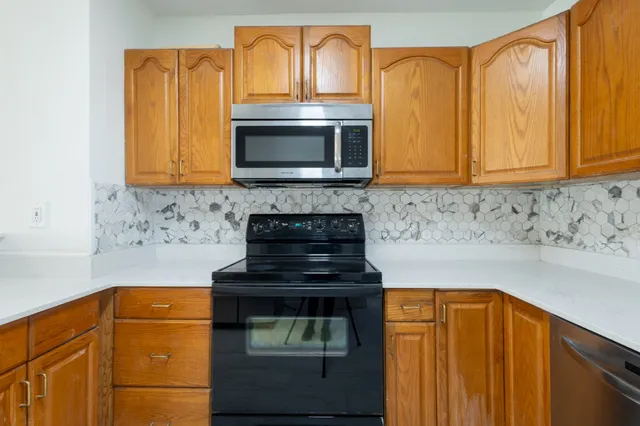 a kitchen with granite countertop wood cabinets stainless steel appliances and a sink