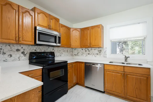 a kitchen with granite countertop wooden cabinets stainless steel appliances and a window