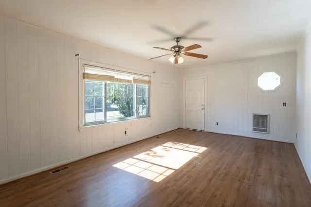 a view of empty room with wooden floor and fan