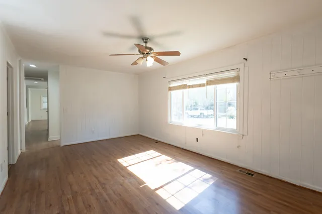 a view of empty room with wooden floor and fan