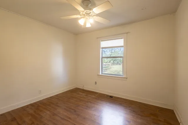 an empty room with a window and wooden floor