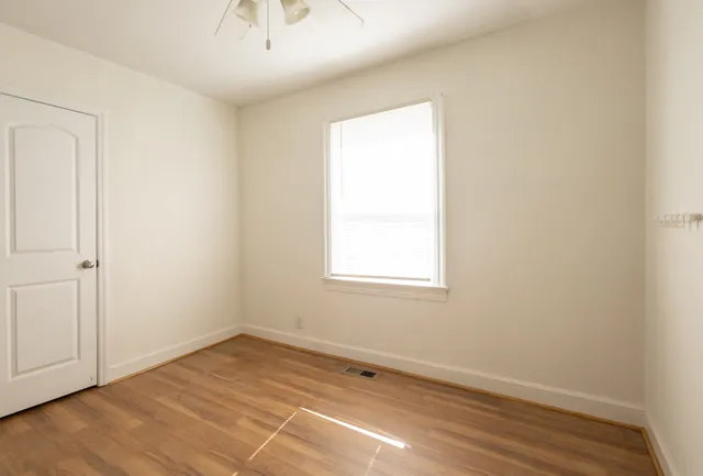 an empty room with wooden floor and windows