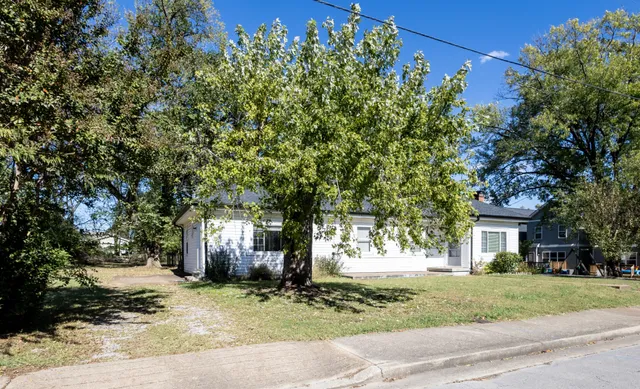 a front view of a house with a yard and tree s