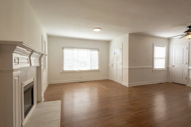 an empty room with wooden floor fireplace and windows
