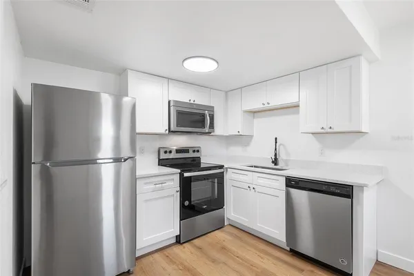 a kitchen with cabinets stainless steel appliances and wooden floor