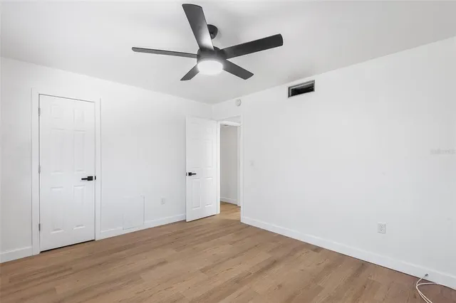 a view of a room with wooden floor and a ceiling fan