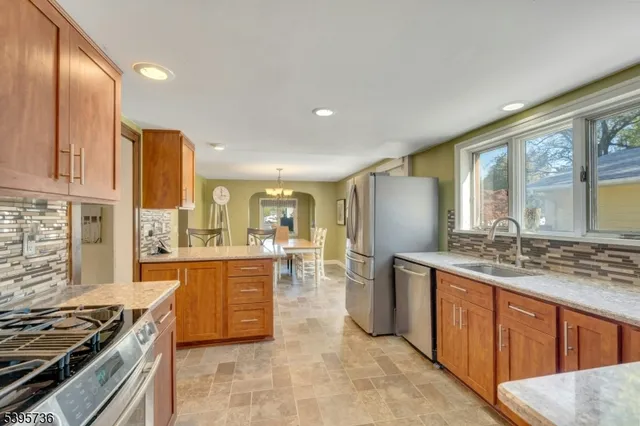 a kitchen with stainless steel appliances granite countertop a stove a sink dishwasher and a refrigerator