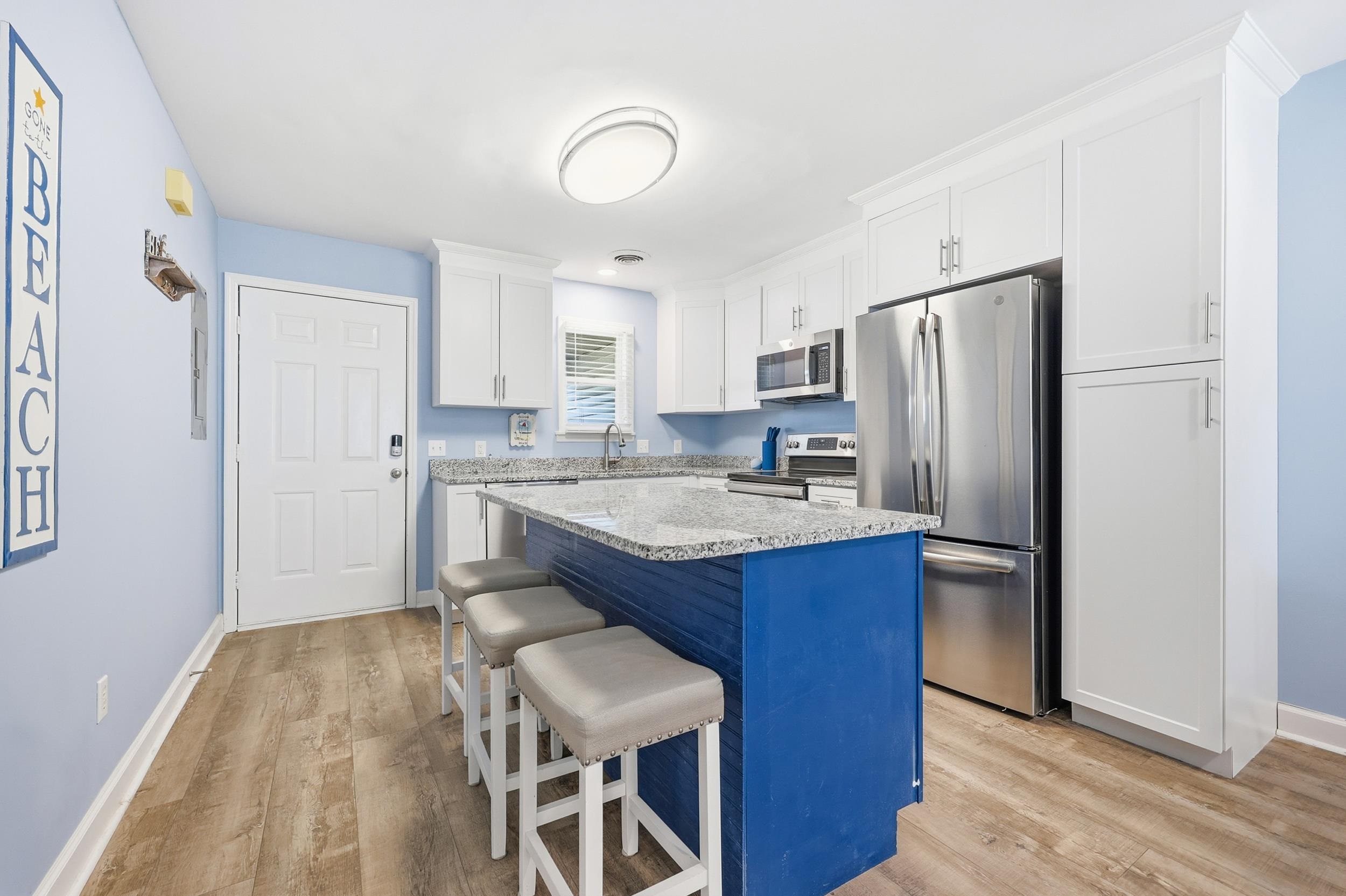 2001 Spring Street, Unit H2 North Myrtle Beach, SC 29582 - Photo 4 of 25 Kitchen featuring stainless steel appliances, a kitchen bar, white cabinetry, light stone counters, and blue cabinetry