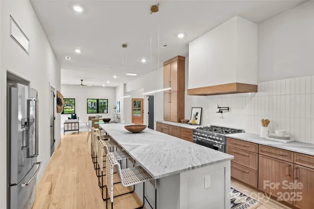 a kitchen with stainless steel appliances granite countertop a stove a sink dishwasher and a refrigerator with wooden floor