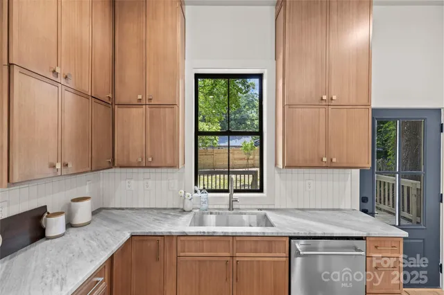a kitchen with granite countertop a sink window and cabinets