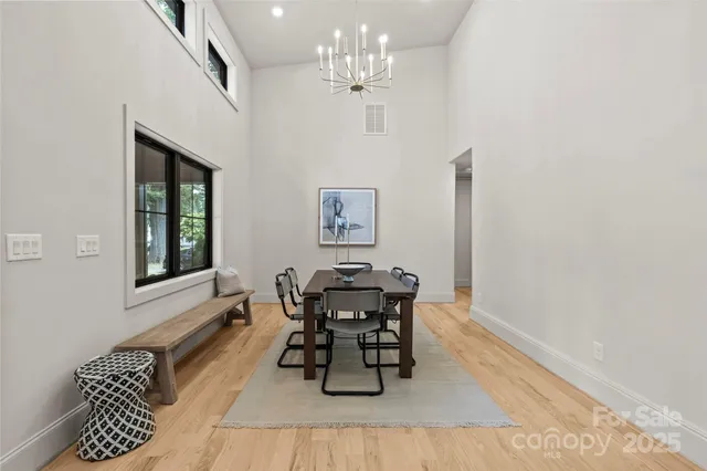 a dining room with wooden floor a chandelier a wooden table and chairs