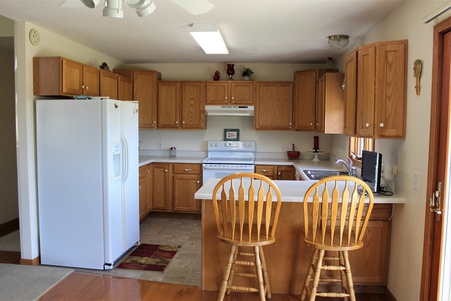 15539 Henry Road, Unit A Morrison, IL 61270 - Photo 8 of 32 a kitchen with stainless steel appliances a refrigerator a sink a stove a microwave and wooden cabinets