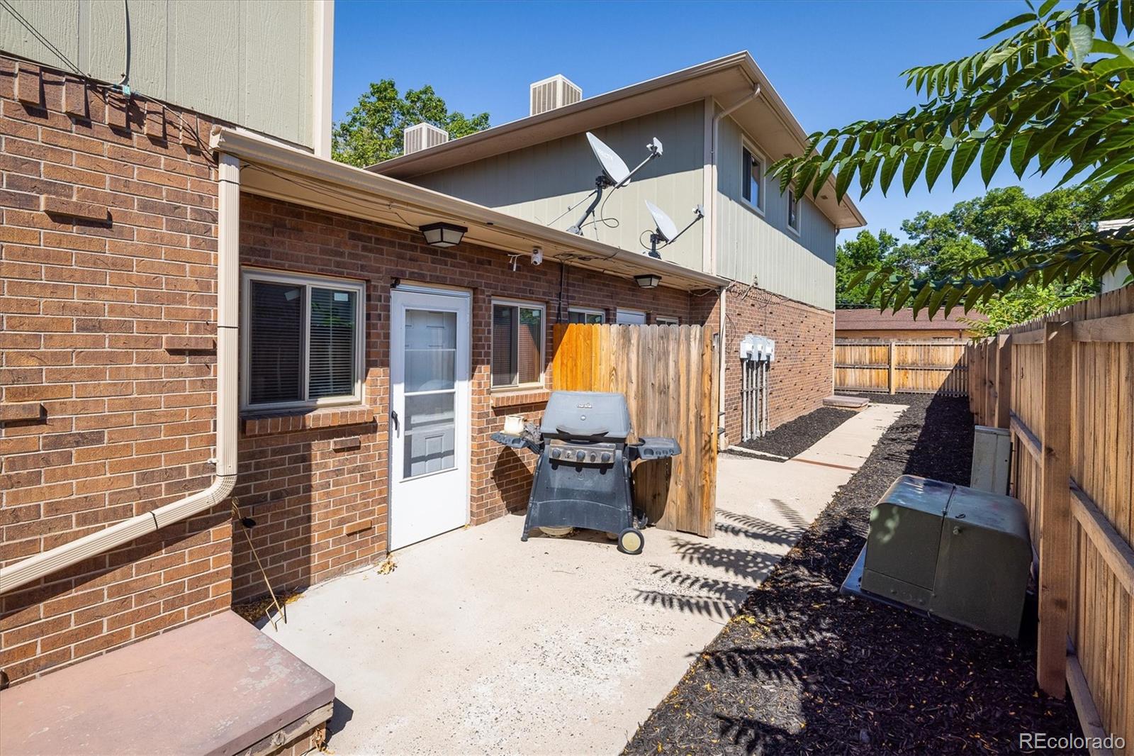 3830 Otis Street, Unit 14 Wheat Ridge, CO 80033 - Photo 19 of 26 a view of a patio with table and chairs potted plants and floor to ceiling window