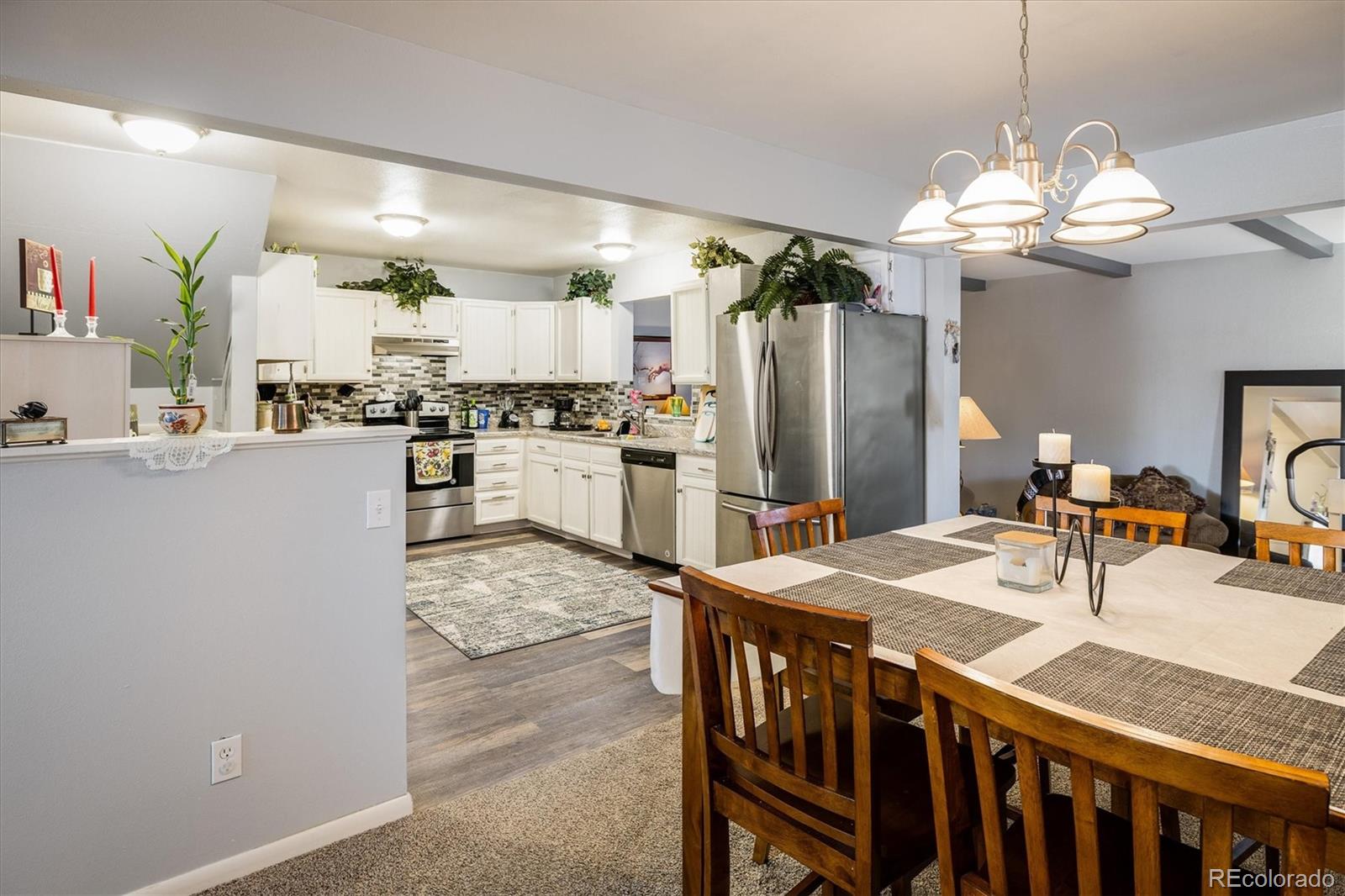3830 Otis Street, Unit 14 Wheat Ridge, CO 80033 - Photo 7 of 26 a kitchen with kitchen island granite countertop a table chairs stove and refrigerator