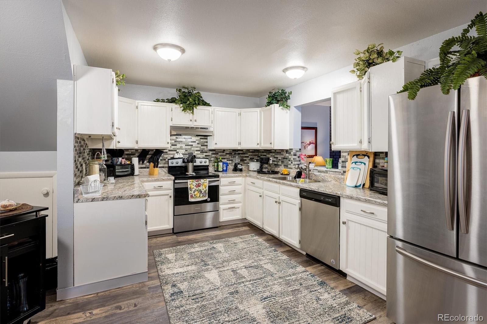 3830 Otis Street, Unit 14 Wheat Ridge, CO 80033 - Photo 8 of 26 a kitchen with stainless steel appliances granite countertop a refrigerator sink and white cabinets