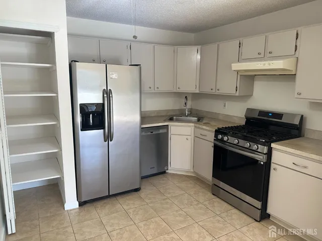 a kitchen with stainless steel appliances granite countertop a stove a refrigerator and a sink