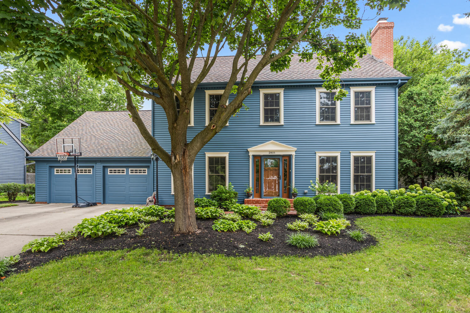 a front view of a house with a garden and trees