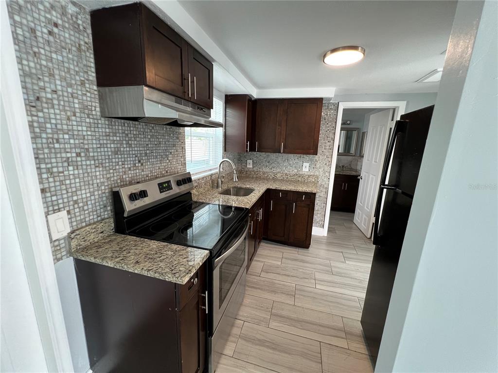5333 Pasadena Drive, Unit 5333 New Port Richey, FL 34652 - Photo 6 of 12 a kitchen with stainless steel appliances granite countertop a stove a sink and a microwave