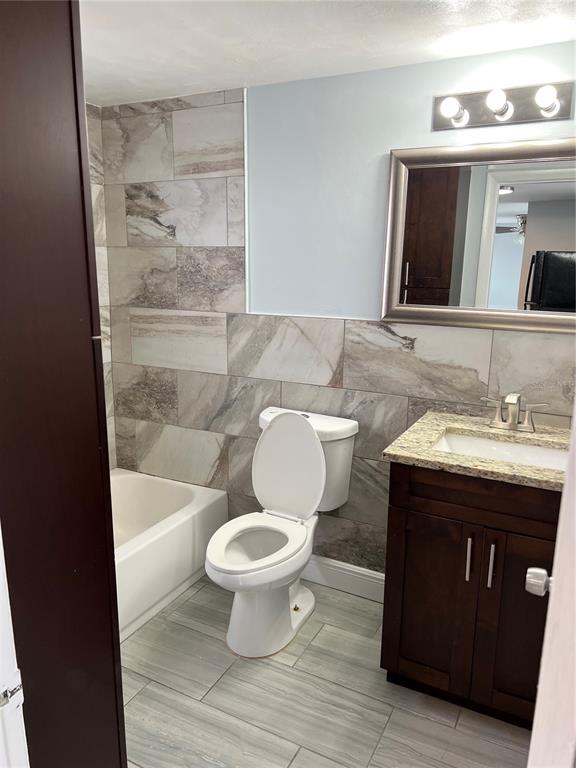 5333 Pasadena Drive, Unit 5333 New Port Richey, FL 34652 - Photo 9 of 12 a bathroom with a granite countertop toilet a sink and a mirror