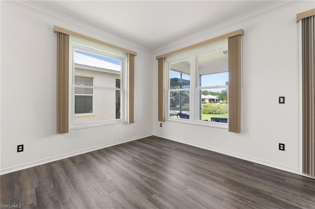 223 Stanhope Circle Naples, FL 34104 - Photo 13 of 41 Bright room featuring wood-finish flooring, white walls, and crown molding