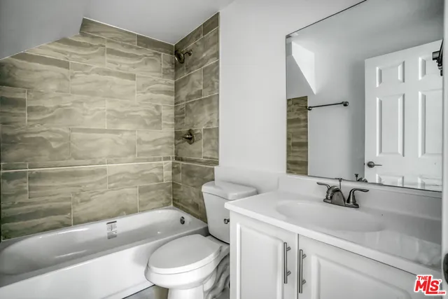 a bathroom with a granite countertop sink a toilet and shower