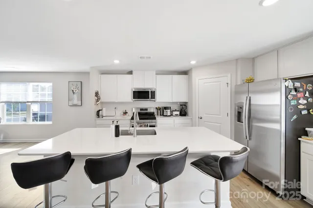 a kitchen with stainless steel appliances kitchen island granite countertop a dining table chairs and granite counter tops