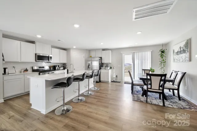 a kitchen with white cabinets and chairs
