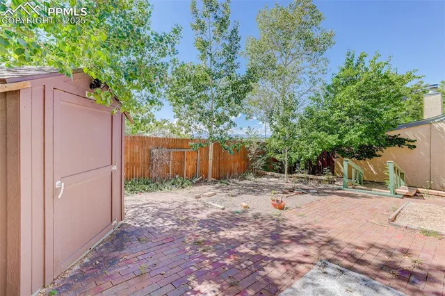 a backyard of a house with large trees and wooden fence