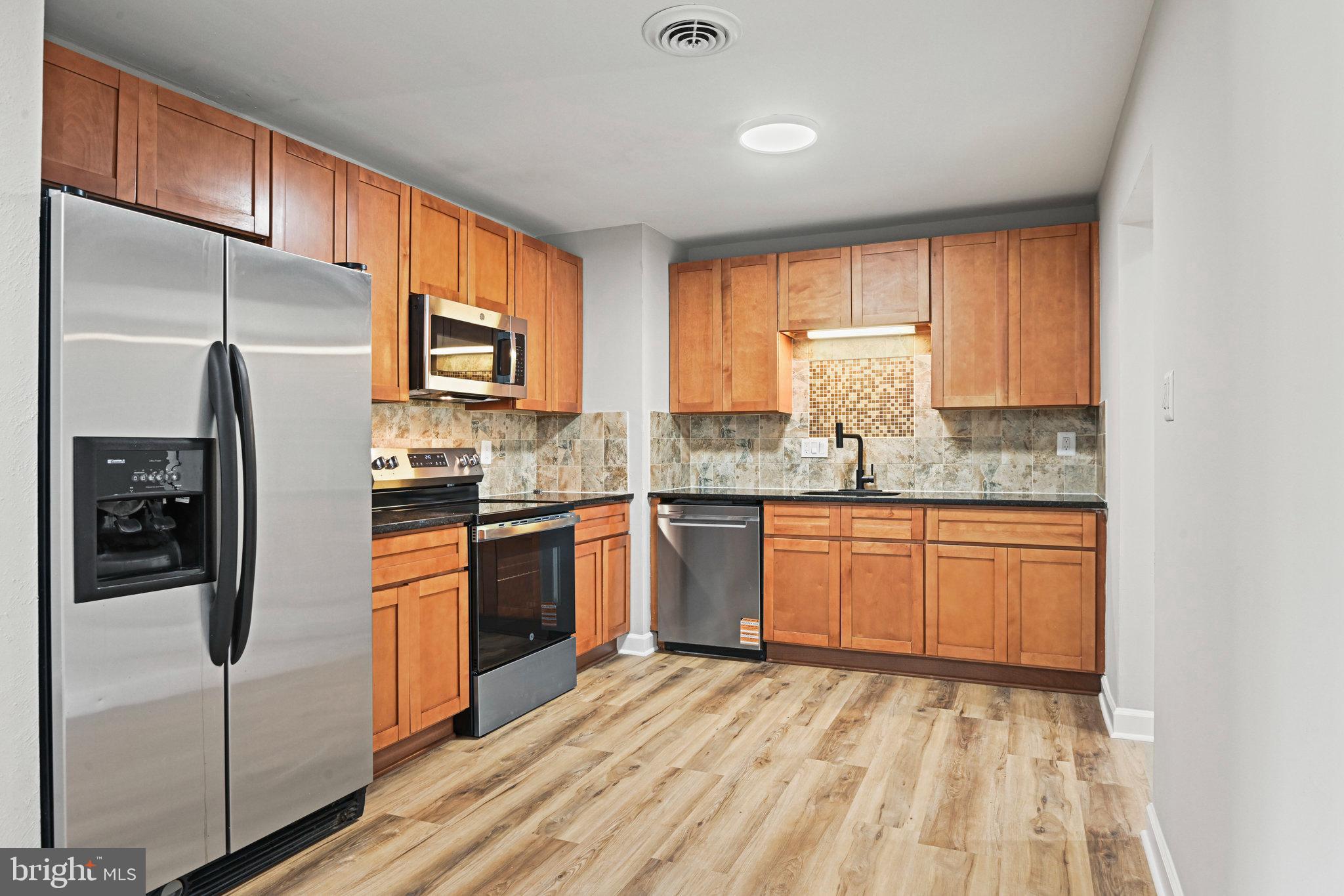 1002 South Buckingham Road Sterling, VA 20164 - Photo 3 of 18 a kitchen with stainless steel appliances granite countertop a refrigerator a sink dishwasher a stove with wooden cabinets and floor